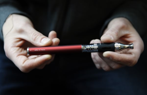 Eric Scheman holds an e-cigarette at Vape store in Chicago, Wednesday, April 23, 2014. The federal government wants to ban sales of electronic cigarettes to minors and require approval for new products and health warning labels under regulations being proposed by the Food and Drug Administration. (AP Photo/Nam Y. Huh)